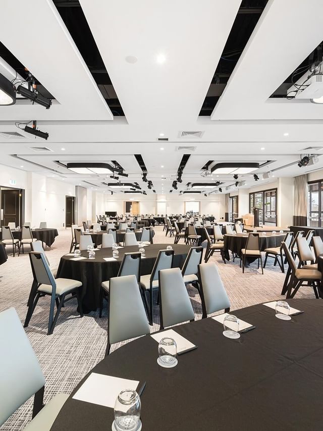 Pacific Ballroom at Elysium Manly, with many black-clothed round tables surrounded by chairs, ideal for Manly event venues