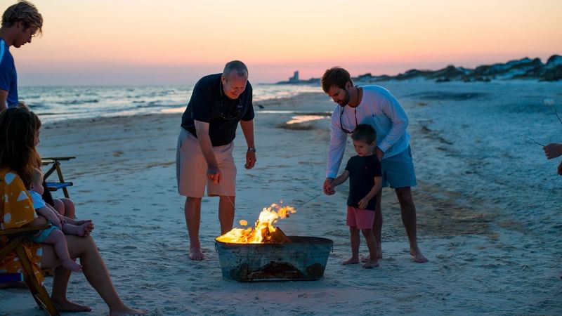 A family burns a bonfire on the beach at WaterColor Inn