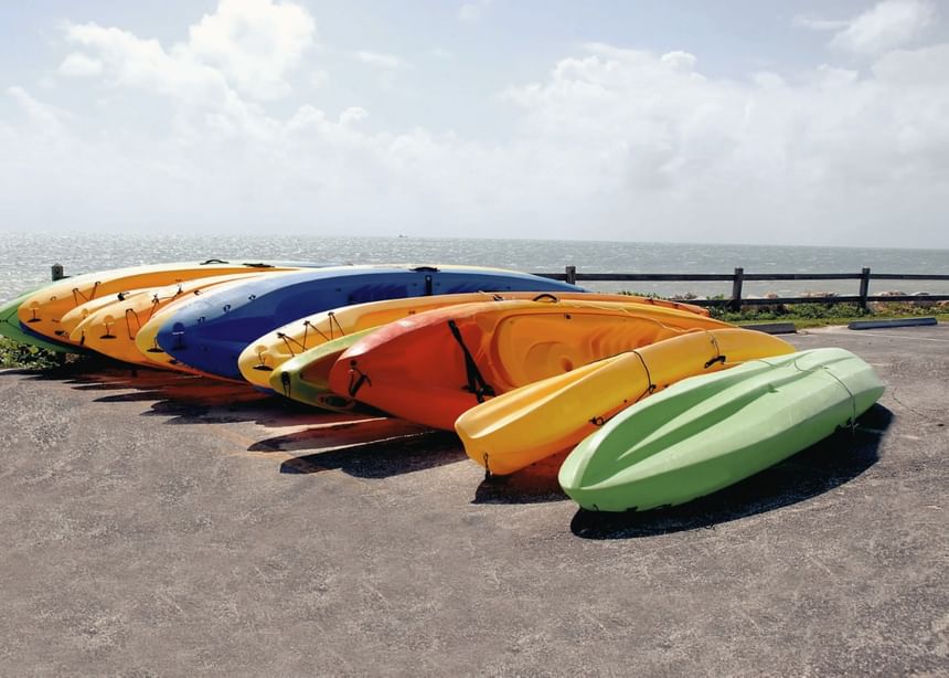 A row of colorful kayaks stacked on a paved surface near Ogunquit Collection