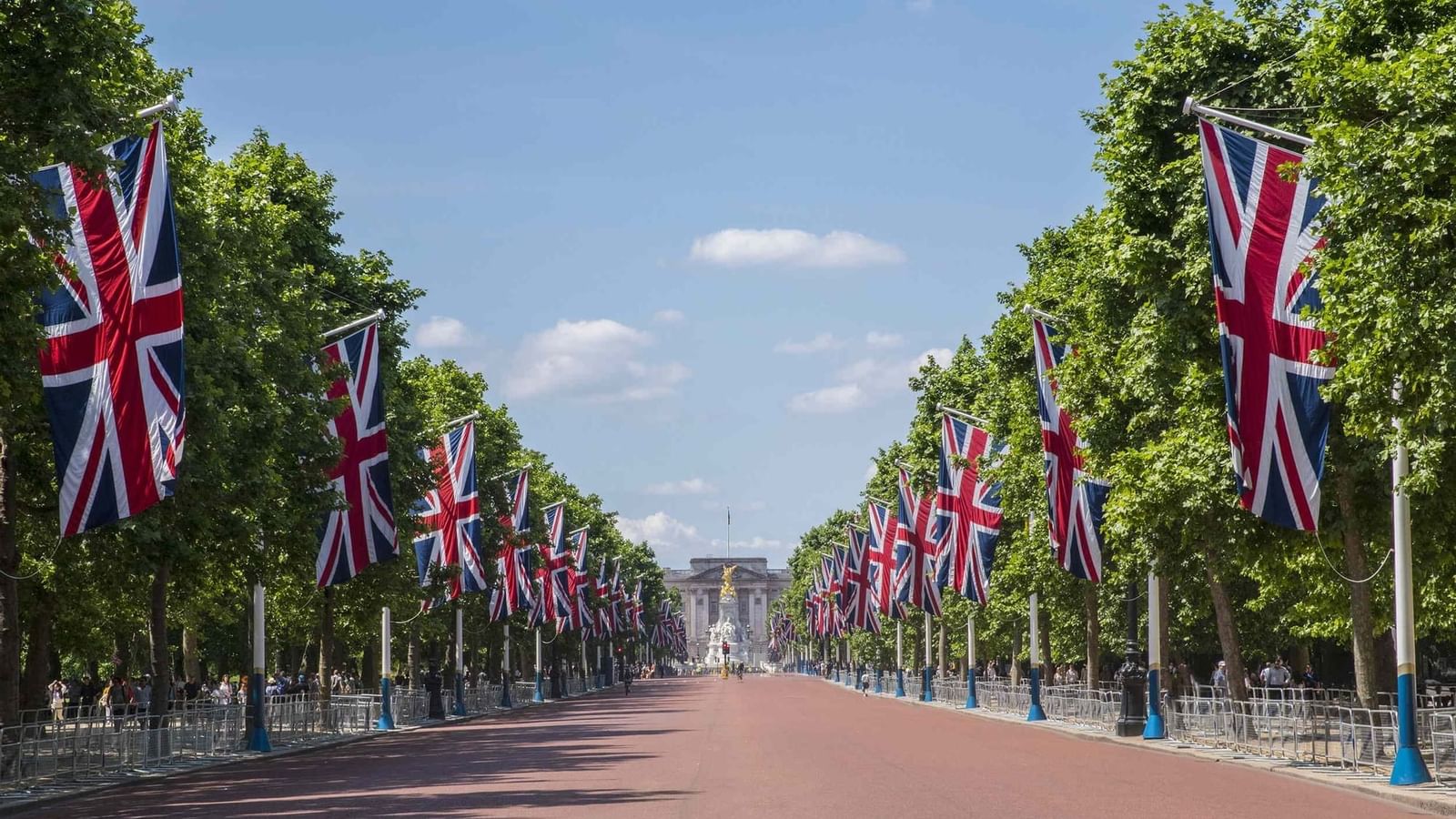 The Mall road lined with flags by green trees under a bright blue sky near The Capital Hotel, Apartments and Townhouse