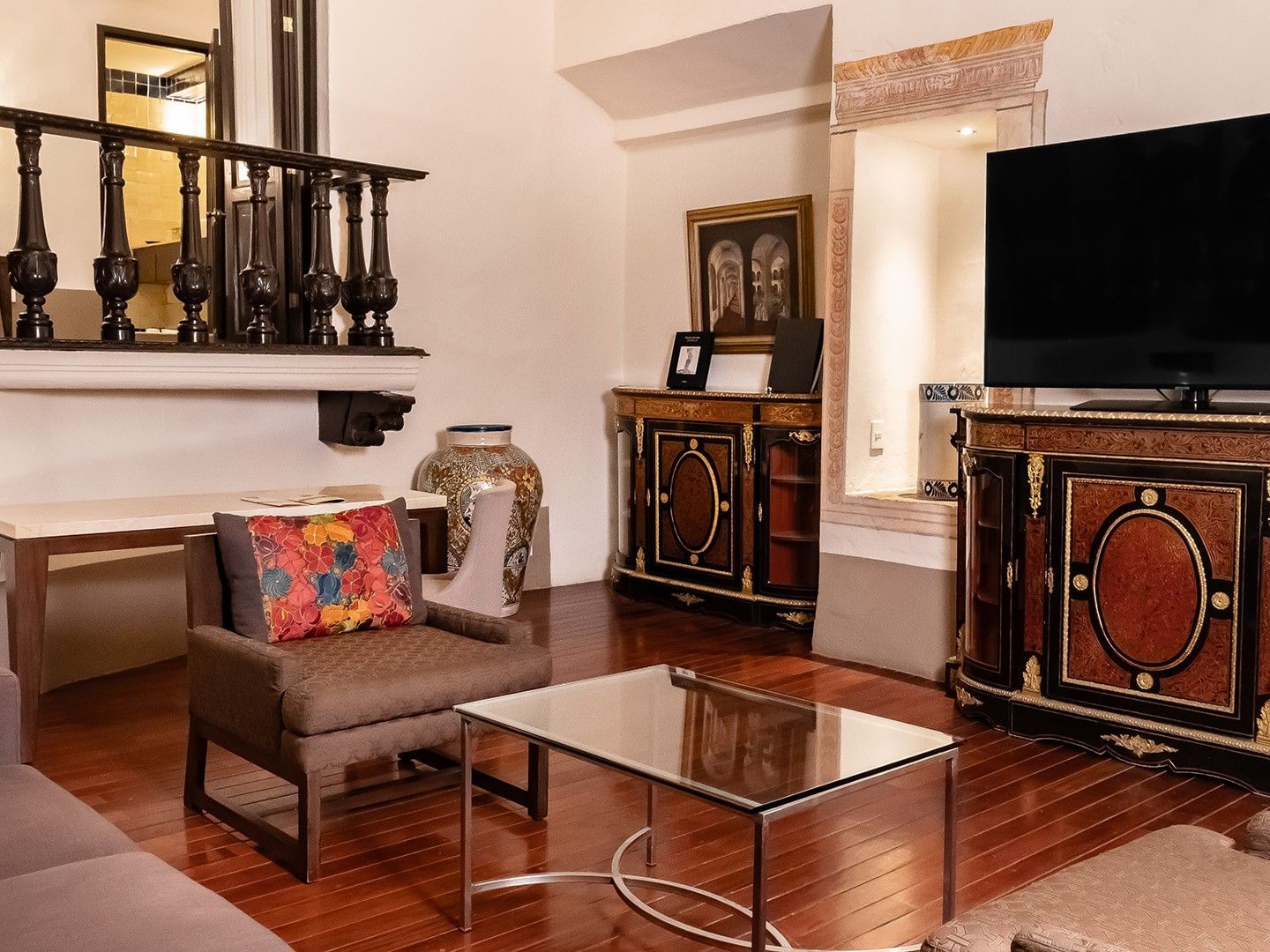Living area with antique cabinets, a glass coffee table, and a brown chair in King Presidential Suite at Quinta Real Puebla