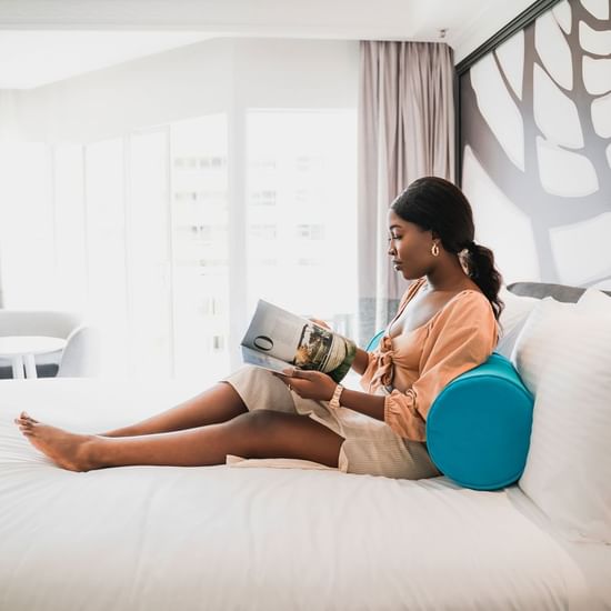 Lady reading a book on a bed at Pullman Cairns