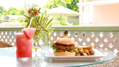 Chicken burger with potato wedges beside glass of watermelon juice in Hott Pott Restaurant at Worthing Court Apartment