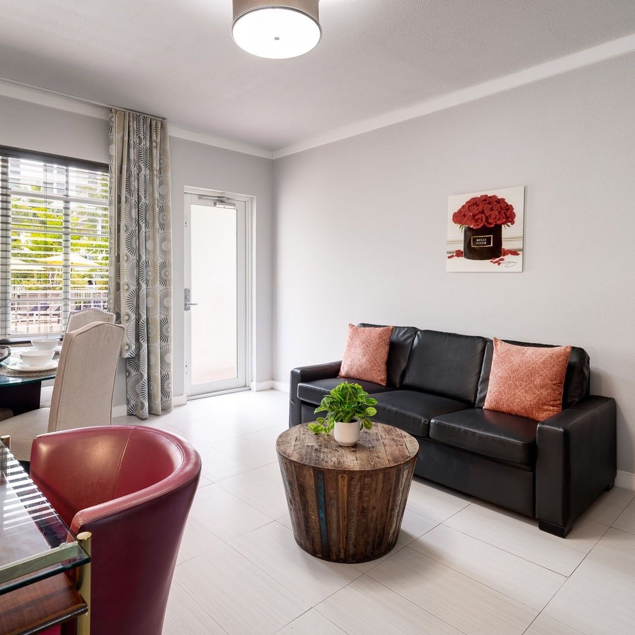 Cozy living room with a black sofa and dining table next to a glass door at the comfortable Tradewinds Apartment Hotel