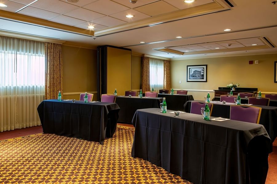 Black clothed tables by purple chairs under recessed lights in Tabor I at Warwick Denver