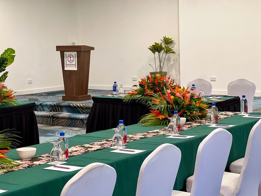 Floral-patterned table runners by white chairs near a wooden podium in a bright conference hall at TokaToka Resort Nadi Fiji