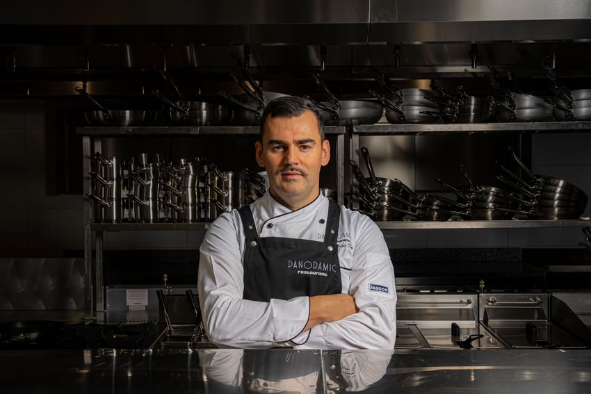 Professional Doru Bar chef in a white uniform posing in a high-end stainless steel kitchen at Ana Hotels
