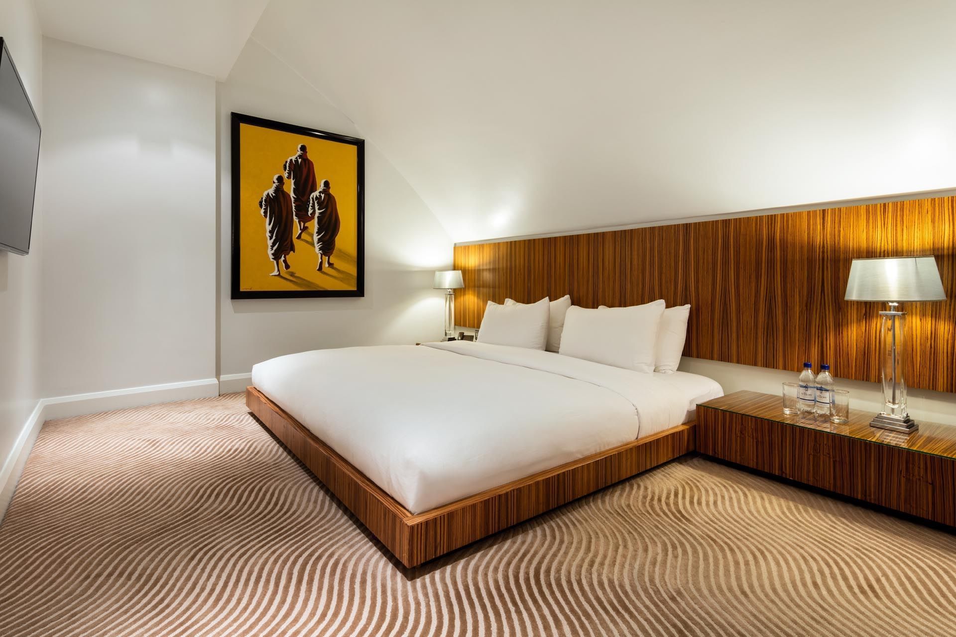 Interior of Duplex Suite with a large bed, unique art, and wood accents at The May Fair Hotel