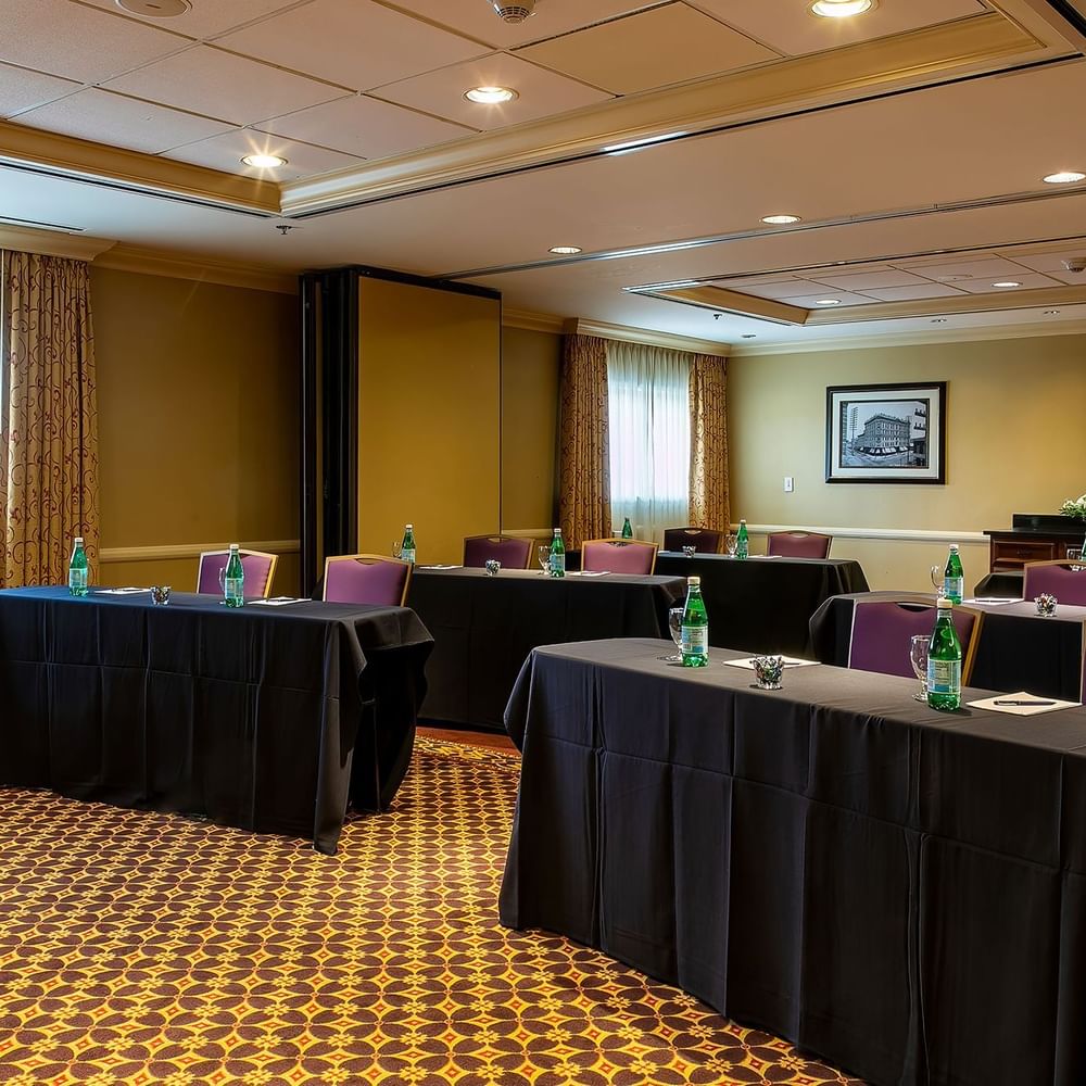 Black clothed tables by purple chairs under recessed lights in Tabor at Warwick Denver