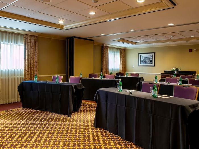 Black clothed tables by purple chairs under recessed lights in Tabor at Warwick Denver