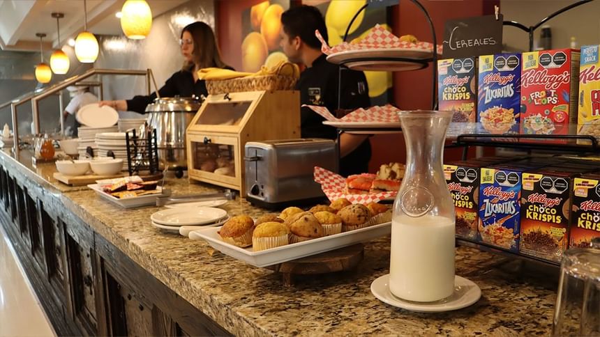 Mostrador de bufé con cereales, magdalenas, tostadas y jarra de leche en Fonda De Hermosillo, Araiza Hermosillo 