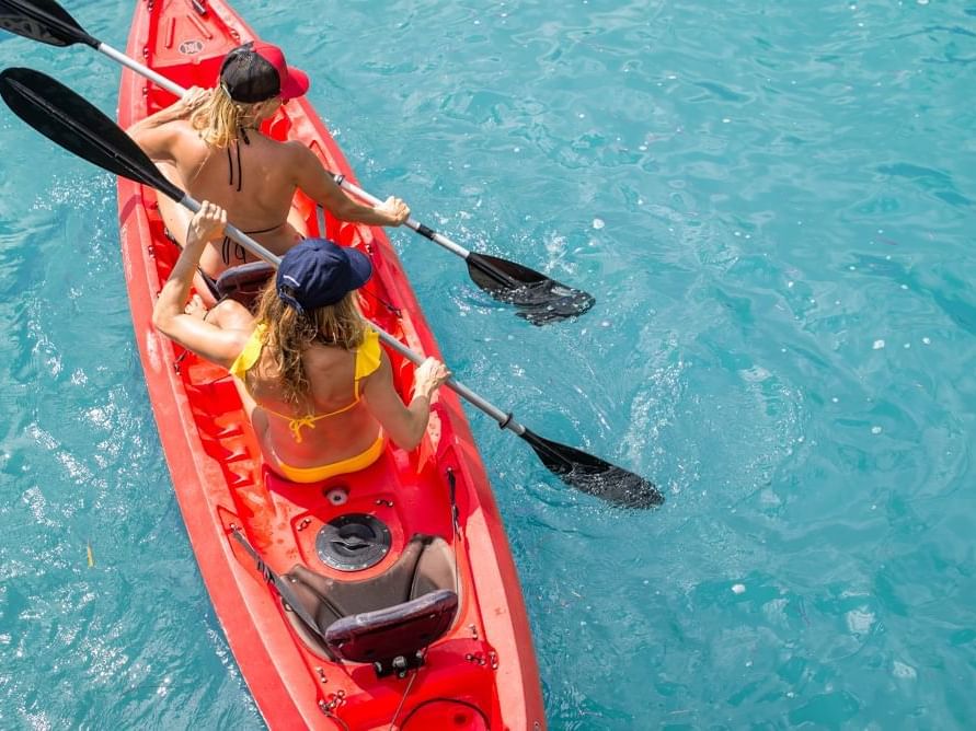 Two women kayaking in ocean near Plymouth Hotel