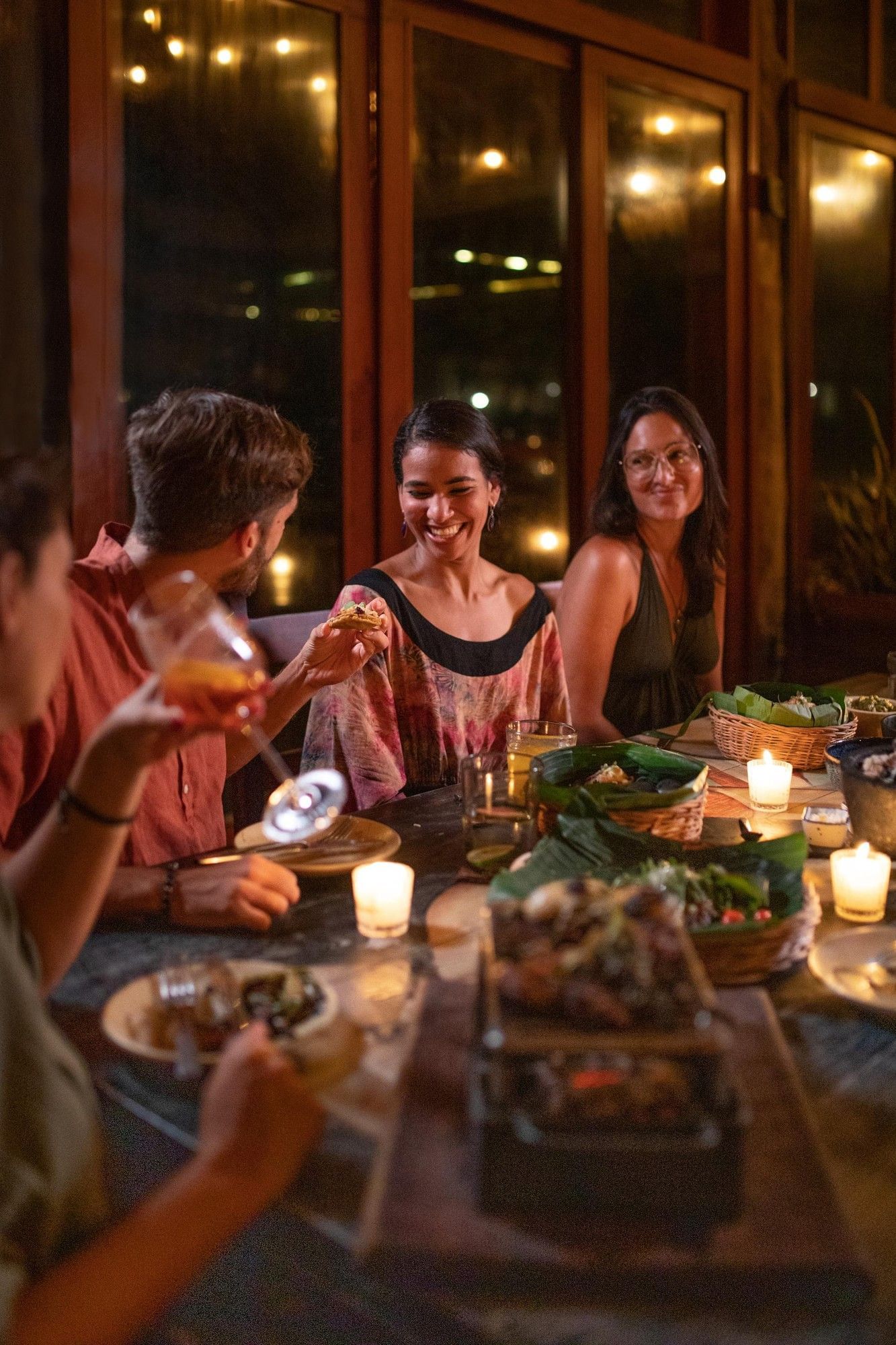 Friends enjoy a dimly lit dinner with delicious food and drinks at a cozy La Zebra Hotel restaurant