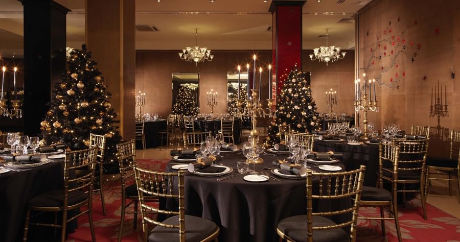 Festive ballroom at The May Fair Hotel set for Christmas, featuring decorated trees and elegant table settings