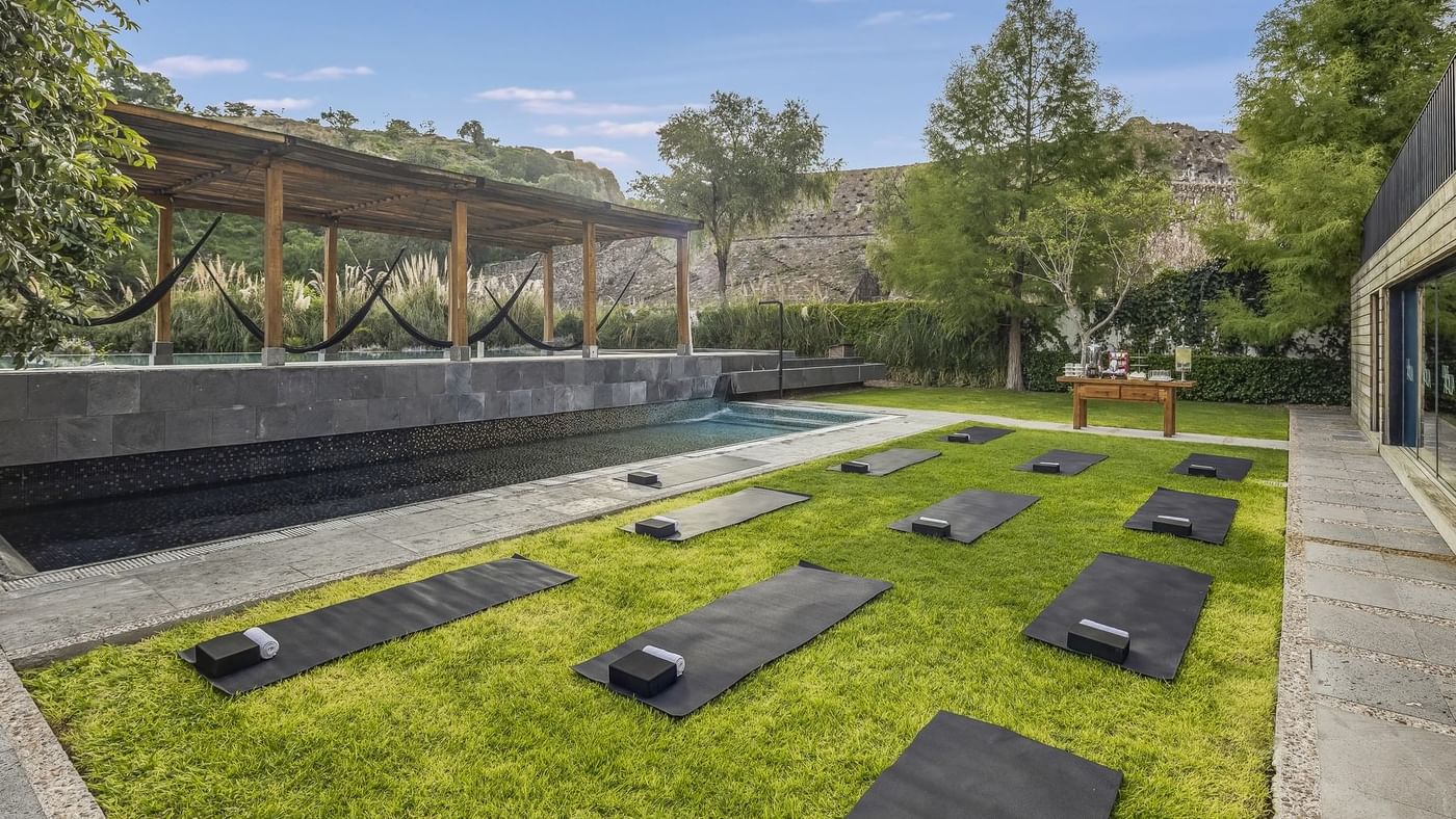 Outdoor wellness space with green lawn, yoga mats & pool at Live Aqua Resorts and Residence Club