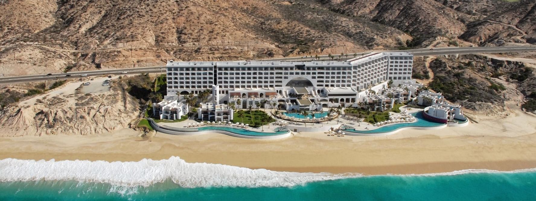 Aerial view of the stunning Marquis Los Cabos Resort, situated on a beach between ocean and desert mountains