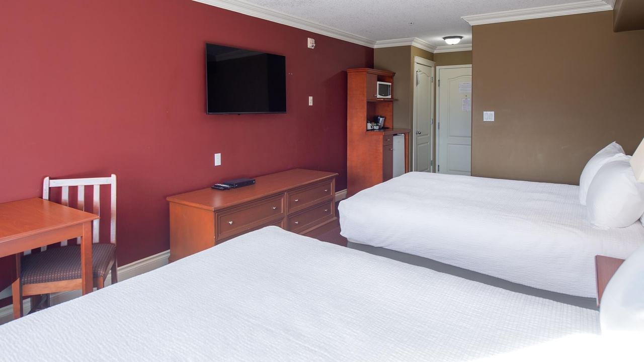 Double room with two beds, wooden furniture, wall-mounted TV, and red accent wall at Coast Edson Hotel.