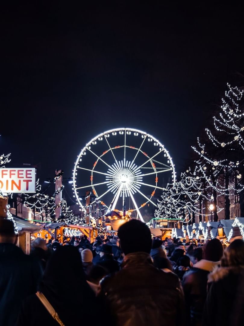 Vibrant Brussels Christmas Market with a bright Ferris wheel and large crowd at night near Hotel Barsey by Warwick