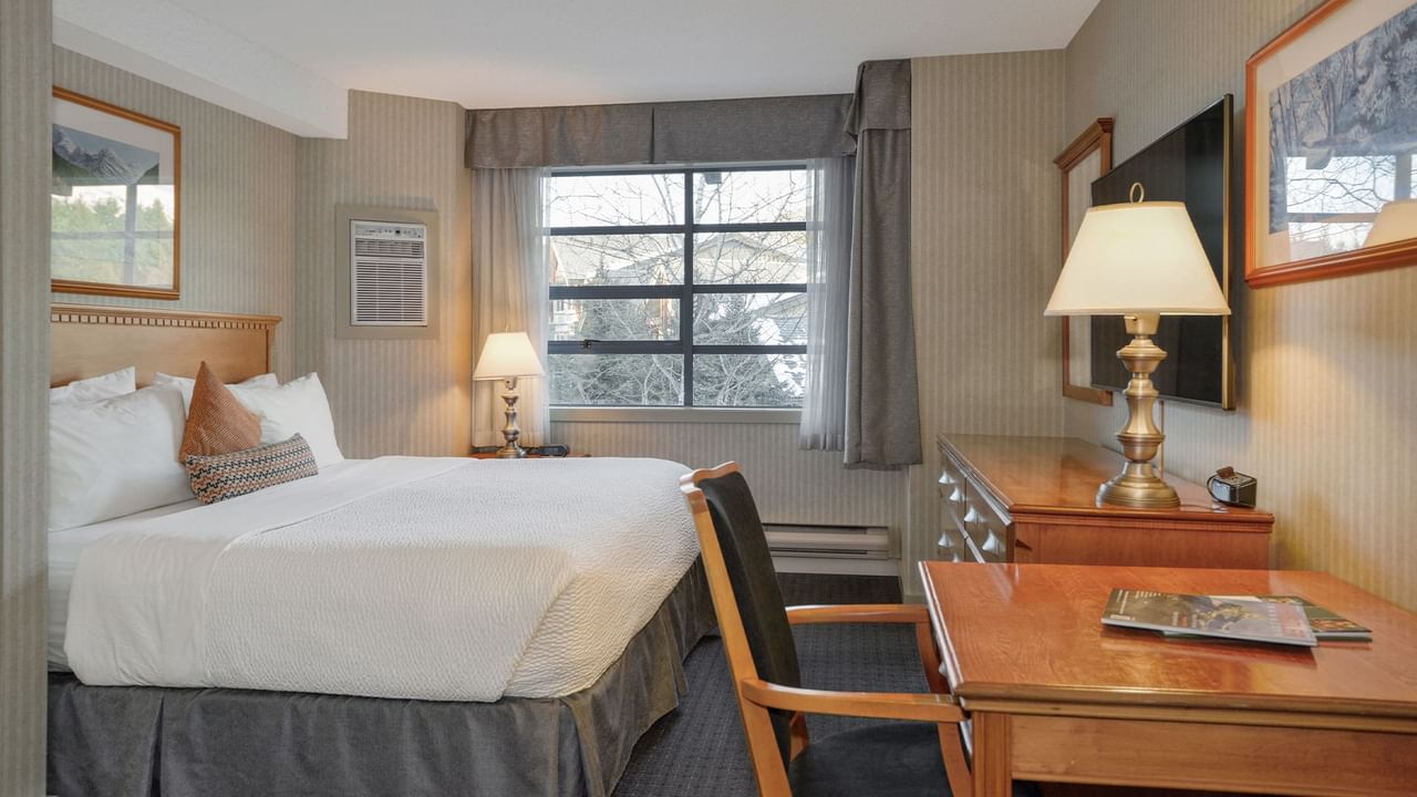 Spacious hotel suite with a king bed, elegant decor, and HDTV.