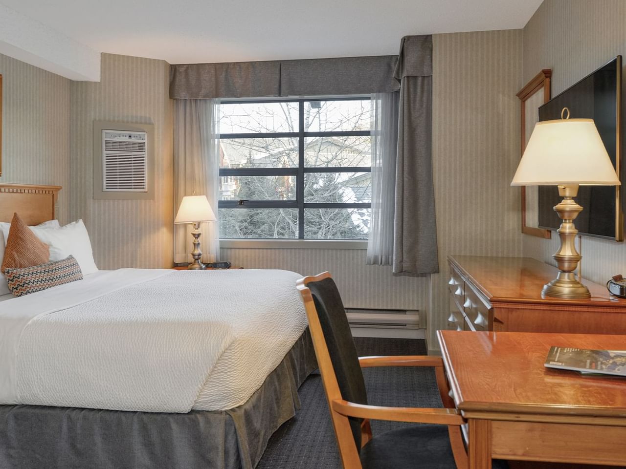 Spacious hotel suite with a king bed, elegant decor, and HDTV.