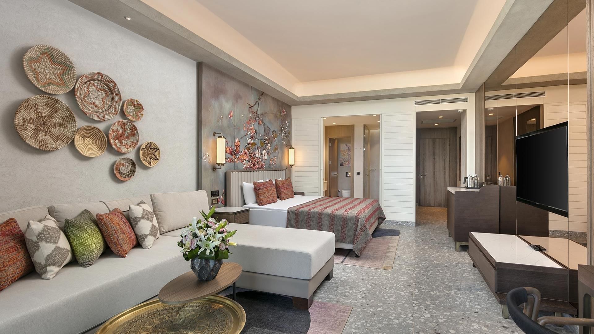 TV lounge area by the bed in Superior Room Sea View with floral wall art at Cullinan Belek