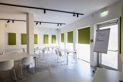 T1 interior with seating, soundproof panels and a welcome sign on a flip chart at Avaneo Hotel Marktredwitz
