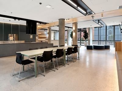 Modern conference room with long table, black chairs, and beige couch at La Trobe University apartments.