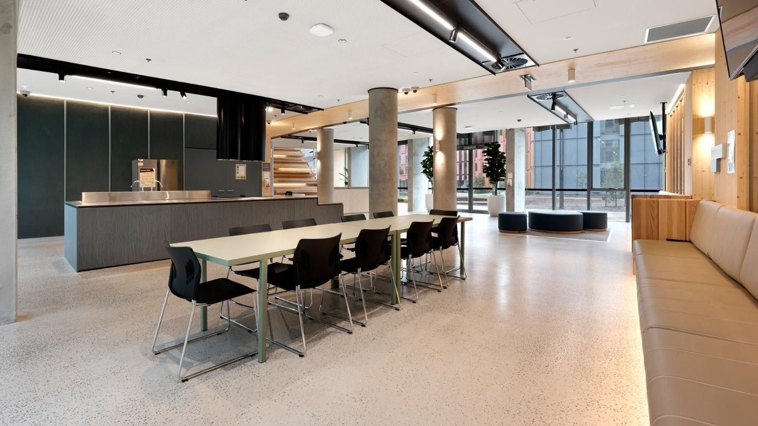 Modern conference room with long table, black chairs, and beige couch at La Trobe University apartments.