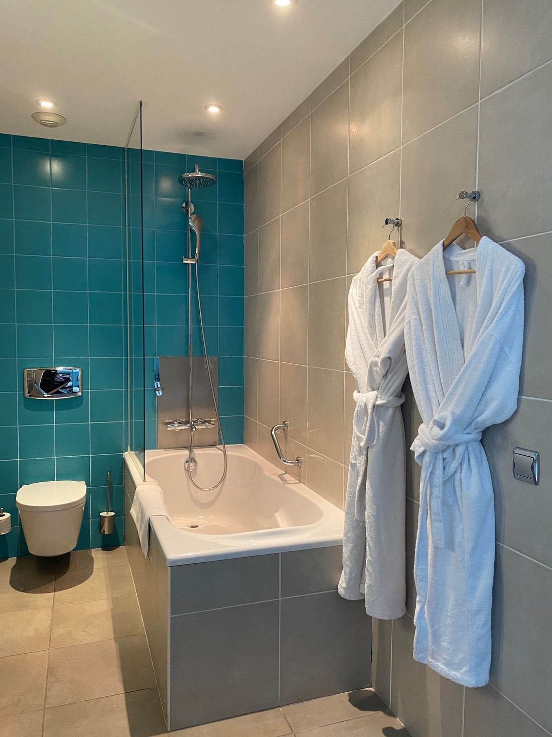 Salle de bain avec baignoire, toilettes et peignoirs suspendus.