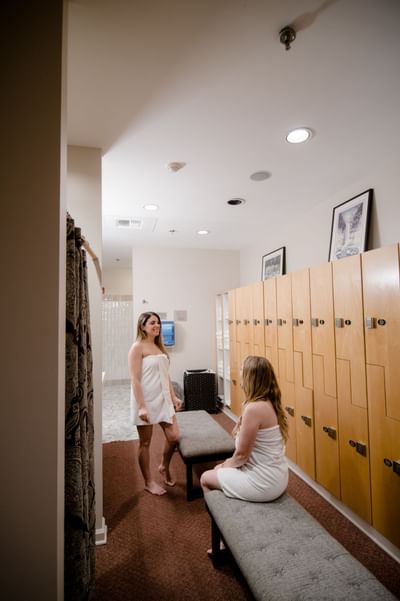 Two women wrapped in towels in a locker room in August Moon Spa at La Tourelle Hotel and Spa