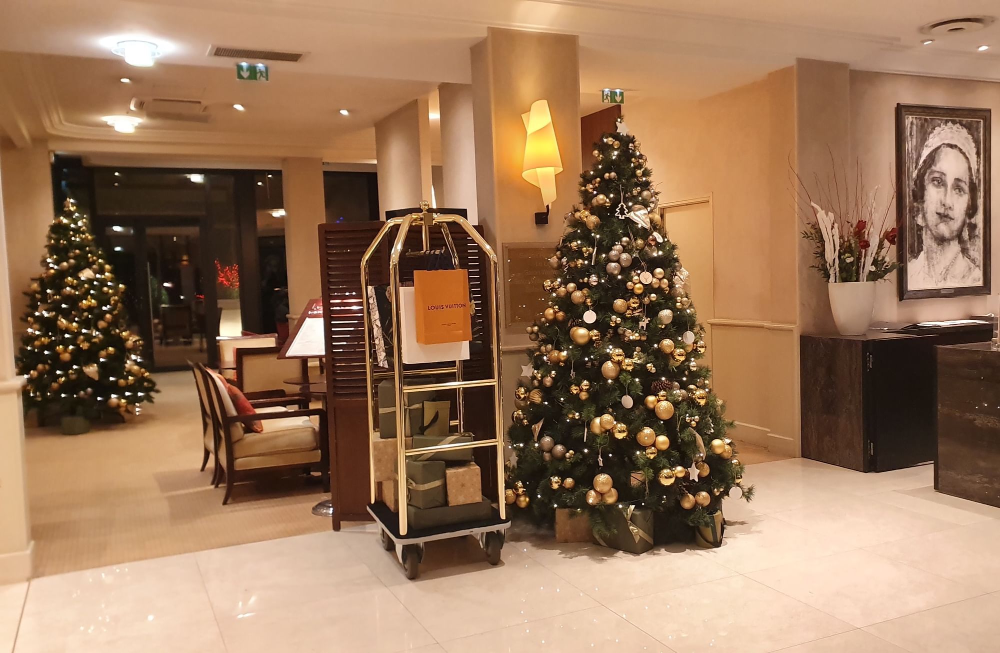 Christmas trees & a luggage cart with holiday gifts in the lobby lounge area at Warwick Reine Astrid - Lyon