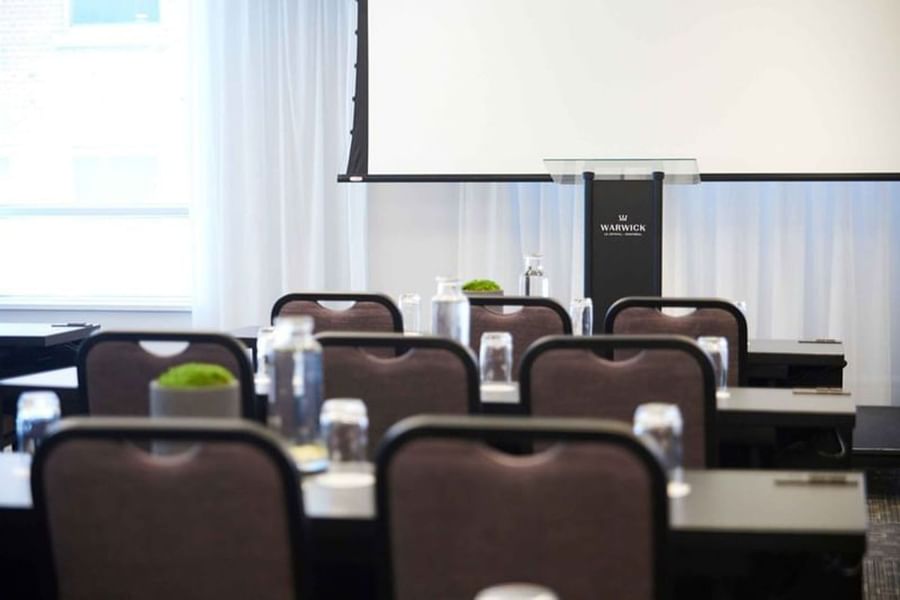 Presentation screen and branded black podium in a bright meeting room at Warwick Le Crystal Montréal