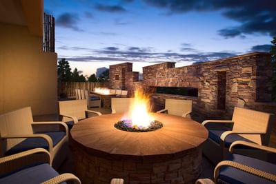 Outdoor patio at Hilton Santa Fe Buffalo Thunder at dusk, with a large circular fire pit and cozy seating areas