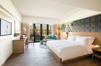 Comfy bed, working area with sofa in Deluxe Room at Eastin Ashta Resort Canggu