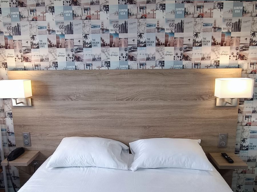 Bed with lamps in Hotel Les Iris at The Originals Hotels