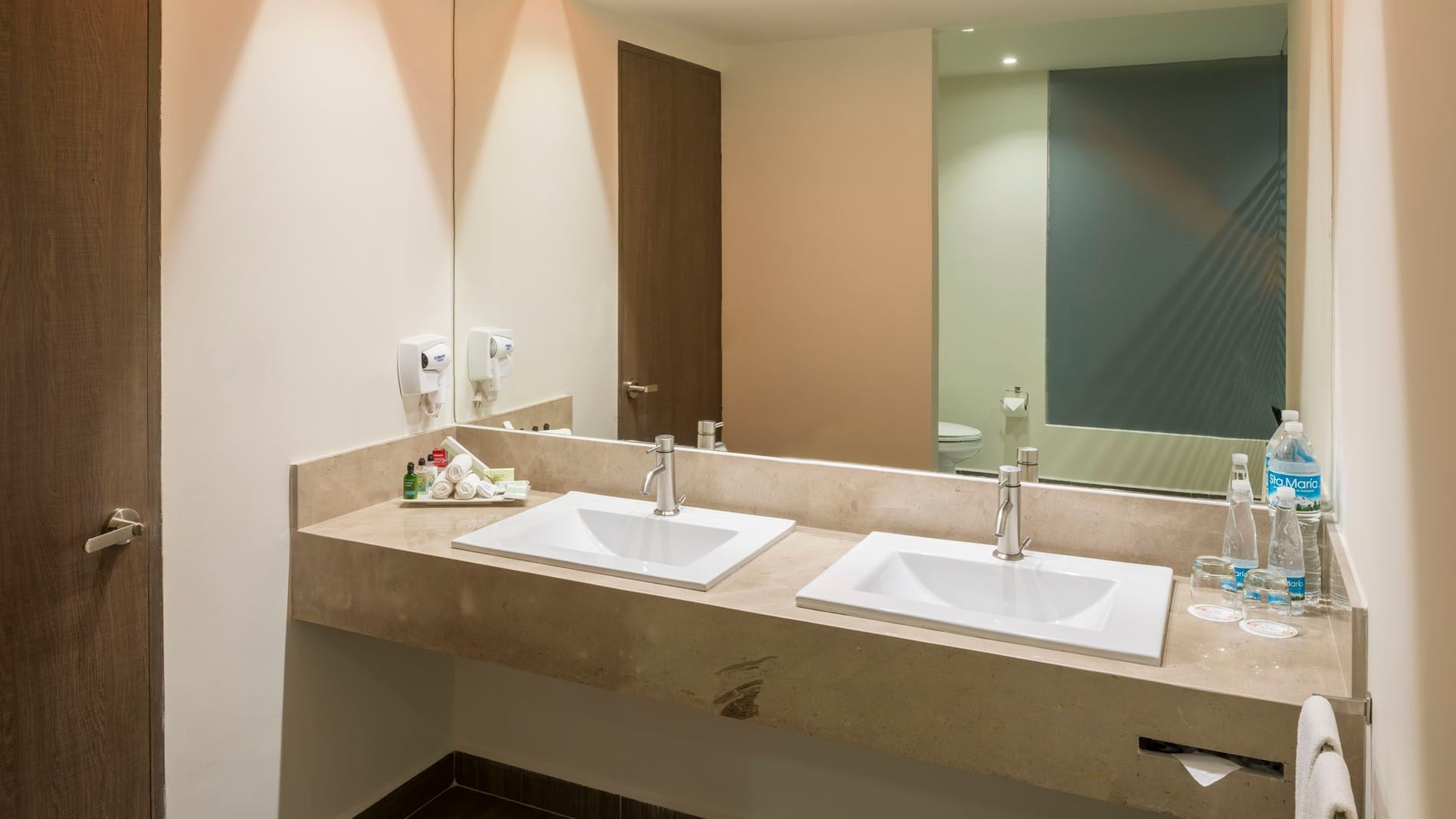 King Presidential Suite restroom with a large mirror, dual sinks, and essential toiletries at Real Inn Celaya