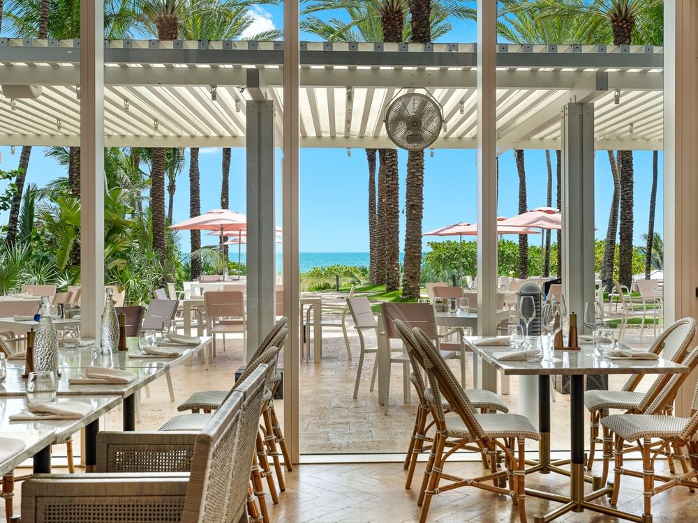 Les tables du restaurant Patio, avec leurs chaises en osier tressé, donnent sur la terrasse extérieure du Grand Beach Hotel Surfside.