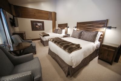 2 double beds, nightstands & chairs in a room at Stein Lodge