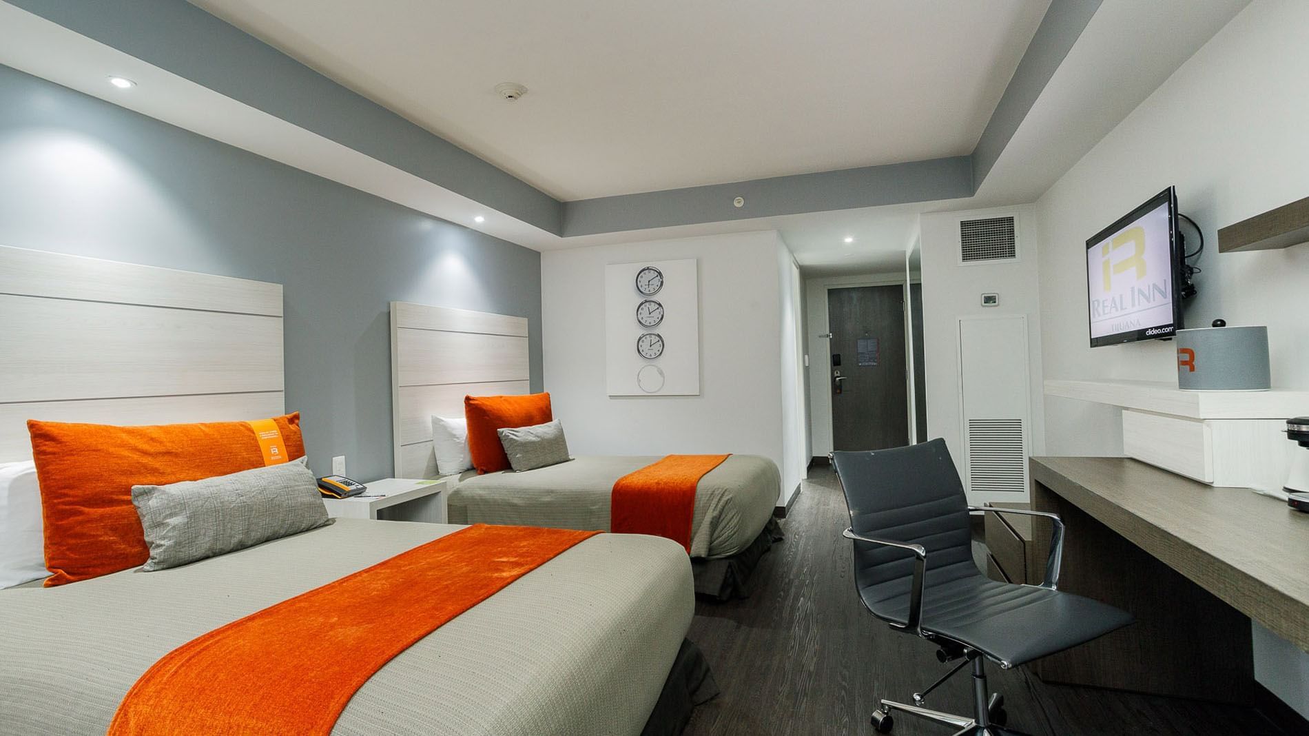 Hanging TV with work desk facing beds by the doorway in the 2 Double Junior Suite at Real Inn Tijuana