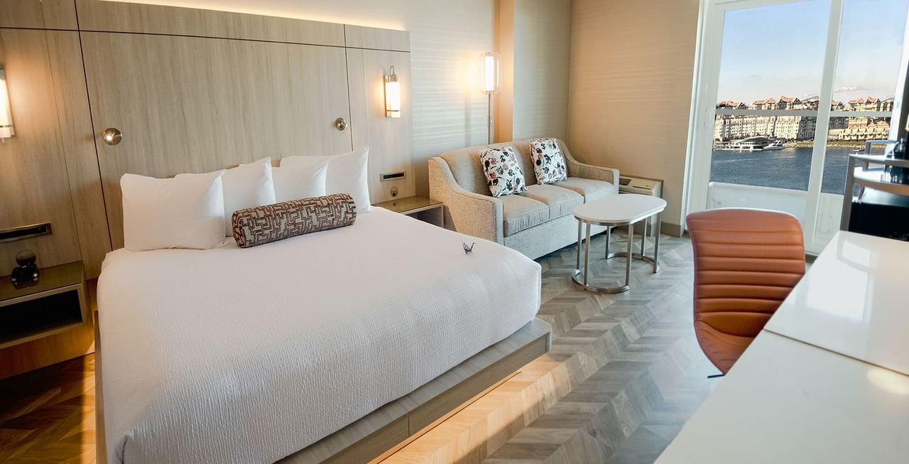 Hotel guestroom with king bed, couch, work desk, chair, and an ocean view
