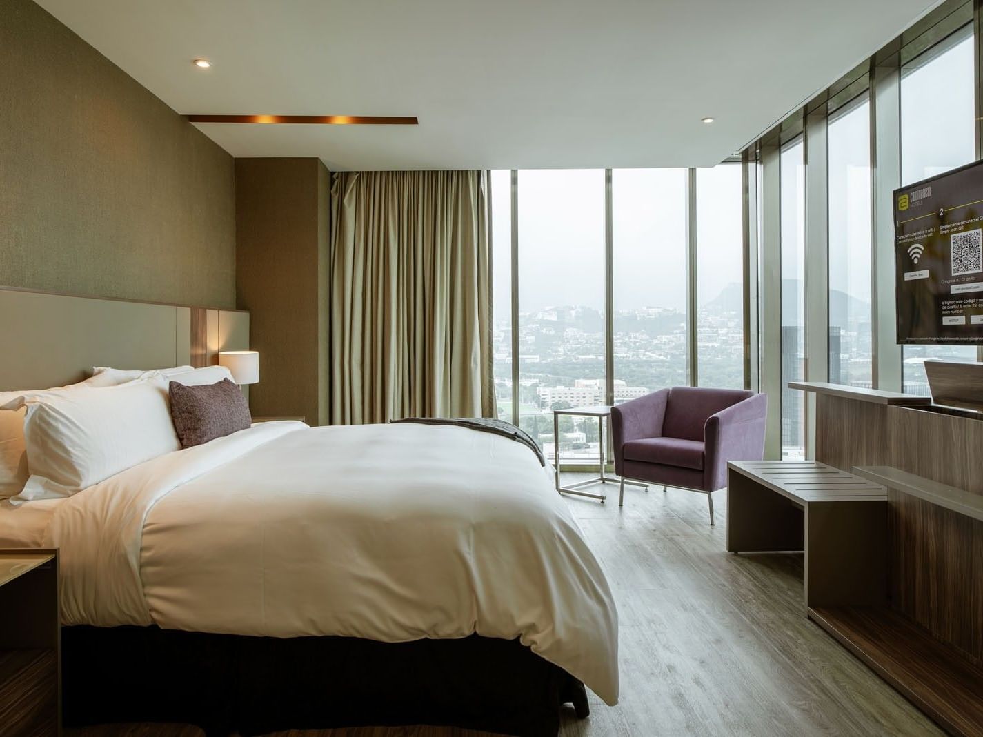King Junior Suite with panoramic city views, purple chair and flat screen TV at Camino Real Fashion Drive, Monterrey