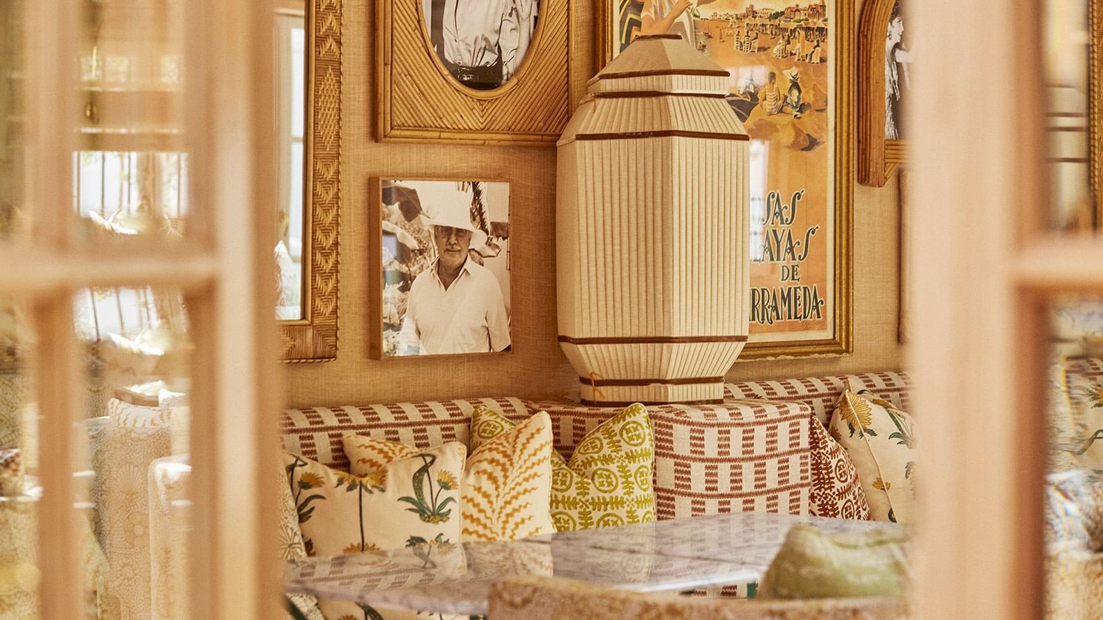 Interior with patterned cushions and vintage posters hanging on the walls, surrounding a woven lamp at Marbella Club