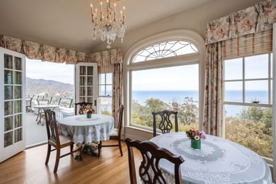 Dining area with wooden floors and large windows overlooking mountains at Mt Ada