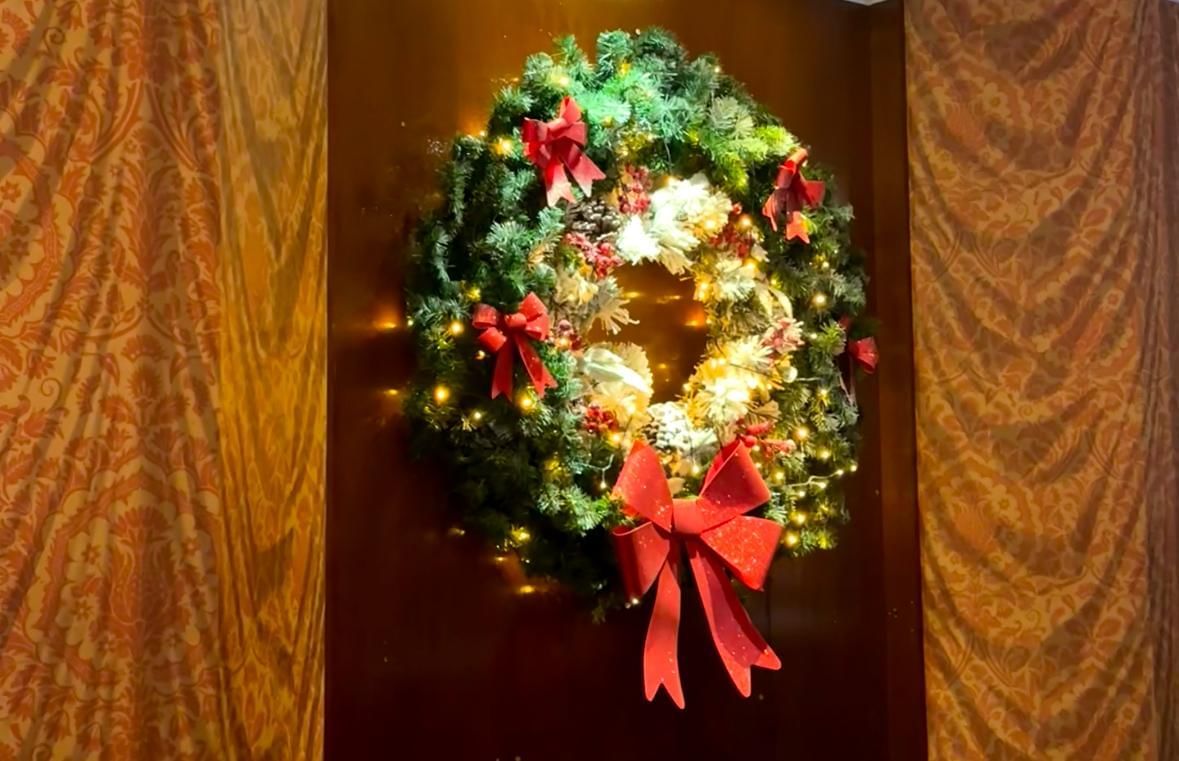 Christmas wreath with lights and red bows on a wooden door at Warwick Brussels