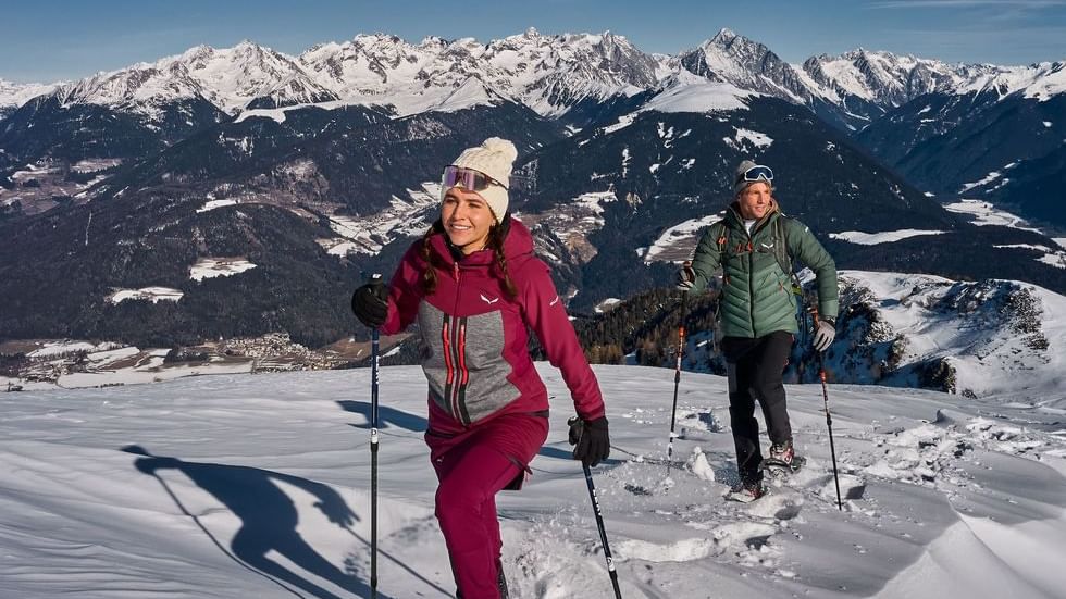 A couple snowshoeing on a mountain near Falkensteiner Hotels