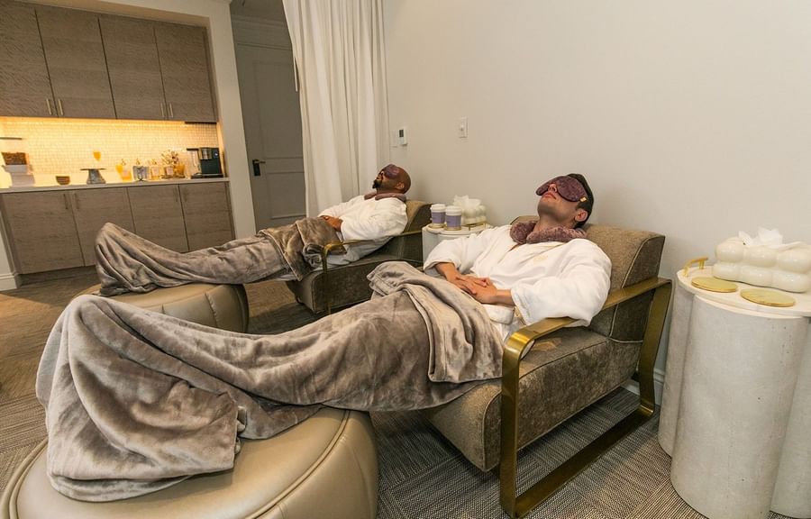 Guests in robes by ottomans under weighted blankets in the quiet spa area at Warwick Melrose Dallas