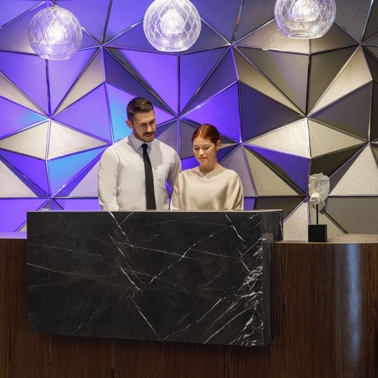 Two receptionists by the front desk in the lobby area at Pullman Sydney Hyde Park