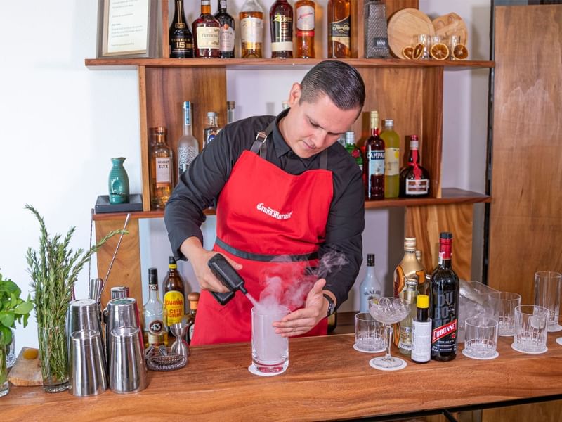 Bartender pouring a smoky liquid into a glass in Club Lounge at Grand Fiesta Americana