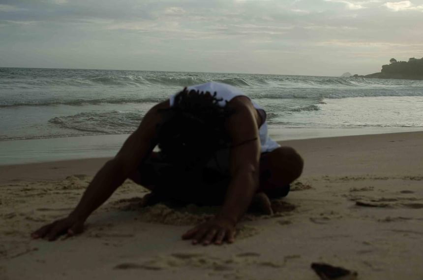 Foto da praia do leblon com um homem praticando alongamento na areia próximo ao mar