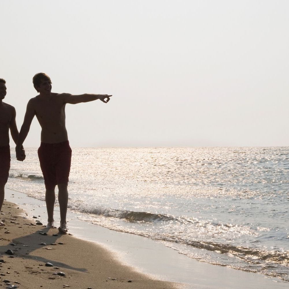 Landscape view of two guys holding hands at the beach near Waikiki Resort Hotel by Sono